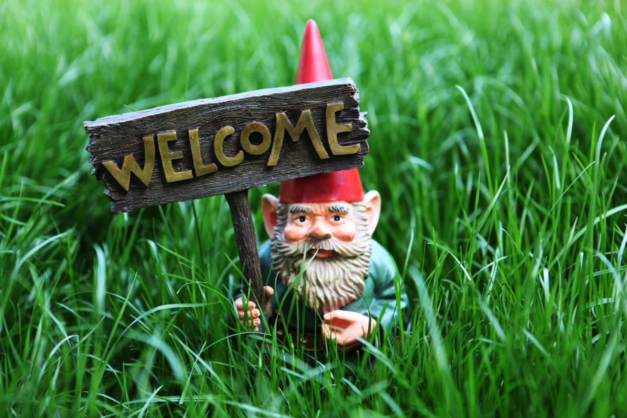 Garden gnome with welcome sign in a grass.