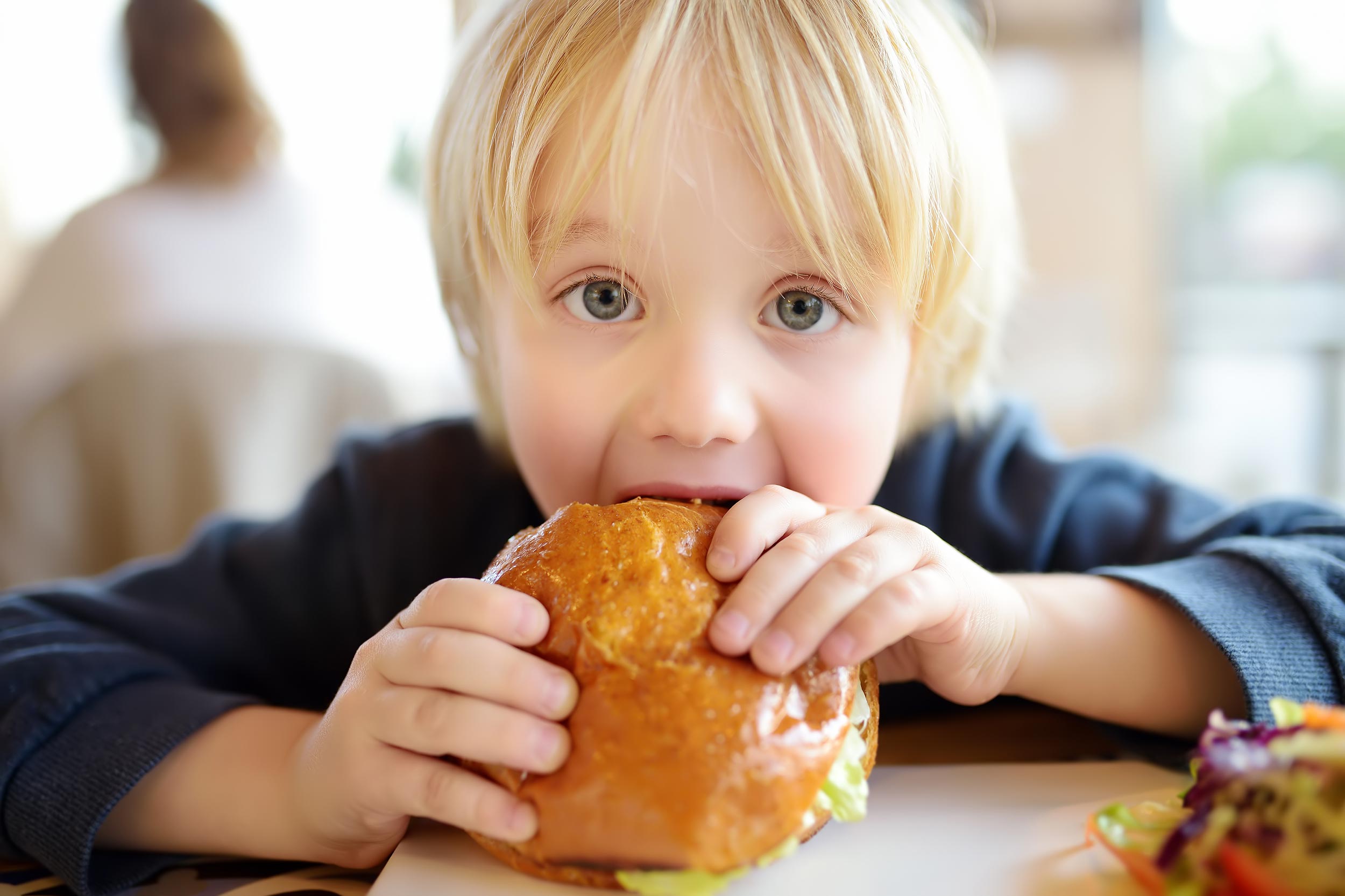 Child eating burger in hotel on holiday